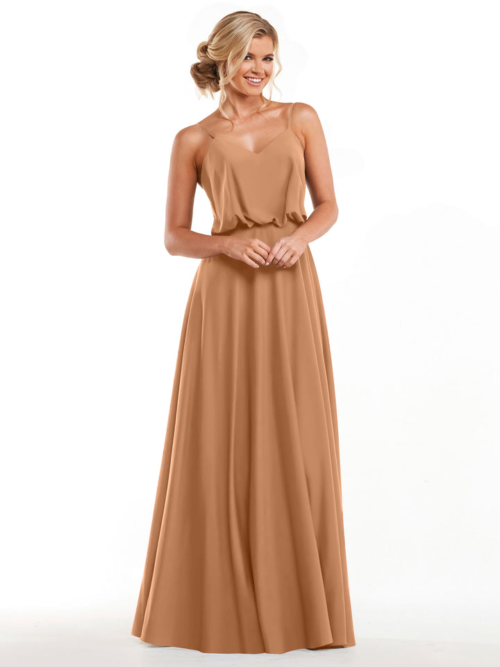A woman with blond hair in a loose updo smiles against a white background, modeling Avery Austin style 83040—a long, sleeveless A-line dress with spaghetti straps in light brown.