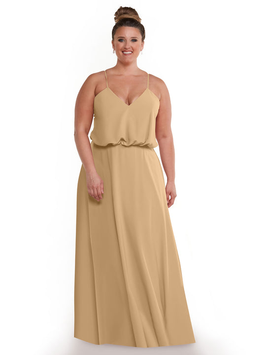 A woman with brown hair in a bun smiles against a white background, wearing Avery Austin's 83040—a sleeveless, floor-length beige A-line dress with thin straps, a flowy skirt, and relaxed waist.