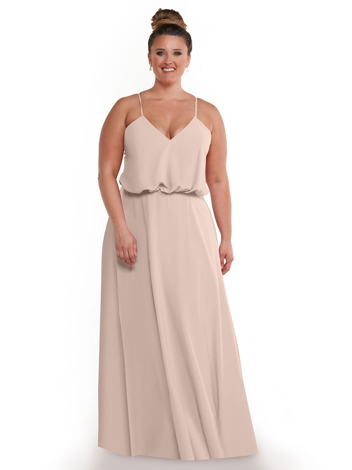 A woman with her hair in a bun wears the Avery Austin 83040, a sleeveless, floor-length A-Line dress in rose pink, with thin straps and a flowy skirt, standing and smiling against a plain white background.