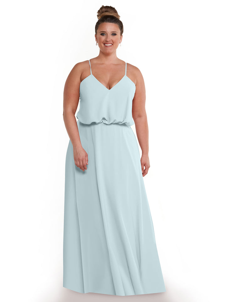 A woman with her hair in a bun smiles while wearing Avery Austin’s 83040—a sleeveless light blue A-line dress with thin straps, relaxed waist, and flowy skirt—posing against a white background.
