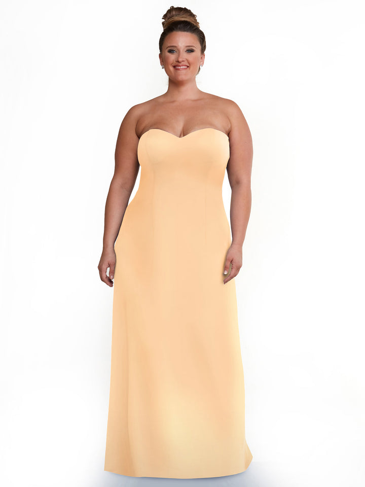 A woman smiles in the Avery Austin 83044 blush gown, featuring a strapless sweetheart neckline and A-line floor-length silhouette, posed against a white background.