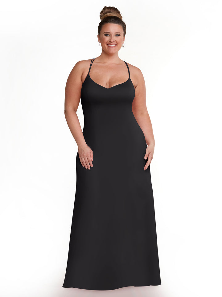 A woman with a bun smiles as she models Avery Austin’s 83045, a long sleeveless black A-Line dress with thin spaghetti straps, standing against a plain white background.