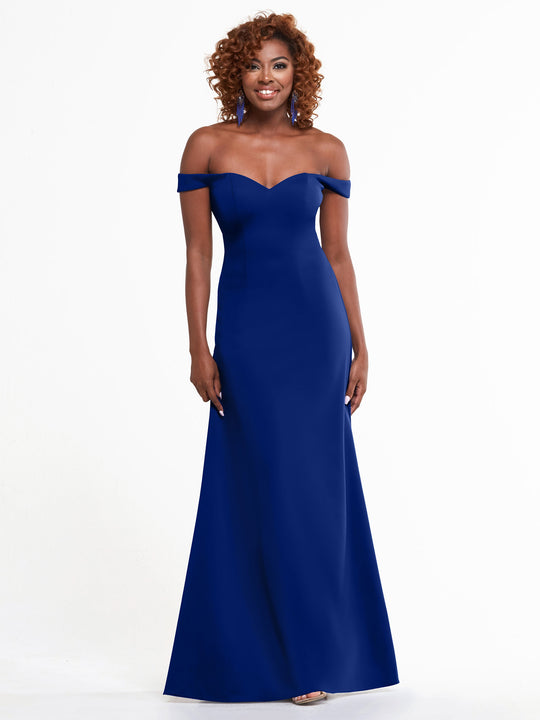 A woman smiles in the Avery Austin 83049 royal A-line off-the-shoulder dress, her curly hair and matching earrings complementing the floor-length gown against a plain white background.
