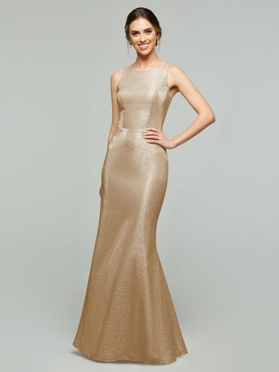 A woman models the averyaustin 84001 - Tried On Sample: a sleeveless, floor-length gold glitter knit gown, smiling with one hand on her hip against a plain light gray background.