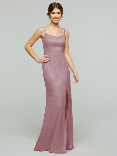 A woman models the averyaustin 84008 - Tried On Sample, a sleeveless, sparkly mauve sheath dress with spaghetti straps and a front slit, posing with one hand on her hip against a plain light gray background.