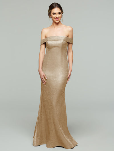 A woman in a Glitter Champagne averyaustin 84010 Tried On Sample mermaid dress stands against a plain gray background, smiling with her hair in an elegant updo.