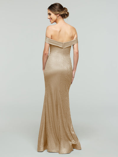 A woman faces away, modeling the averyaustin 84010 Tried On Sample—an off-the-shoulder, floor-length mermaid dress in shimmery gold. Her hair is styled in an elegant low bun against a plain light gray background.