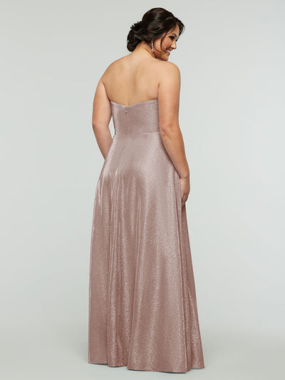 A woman models the averyaustin 84012 - Tried On Sample, a strapless shimmery rose gold A-Line gown with a sweetheart neckline. She stands with her back to the camera, dark hair up, against a plain light background.