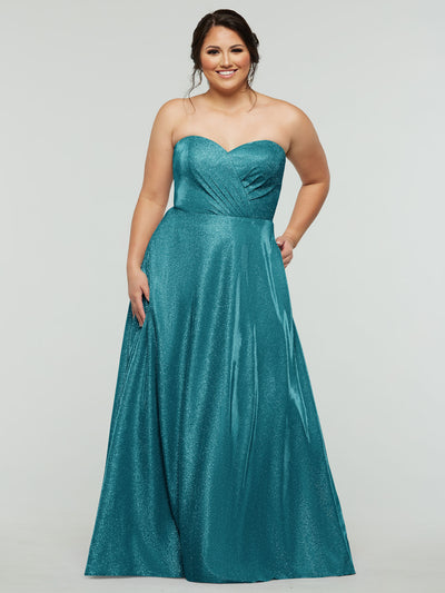 A woman wearing the averyaustin 84012 - Tried On Sample A-Line gown in Glitter Teal with a strapless, fitted bodice and flared skirt smiles against a plain light gray background.